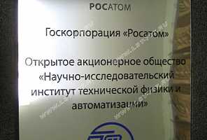 Фото фасадной металлической таблички с надписями, изготовленной из зеркальной нержавеющей стали под серебро с применением цветной эмалевой заливки текста и логотипа.
